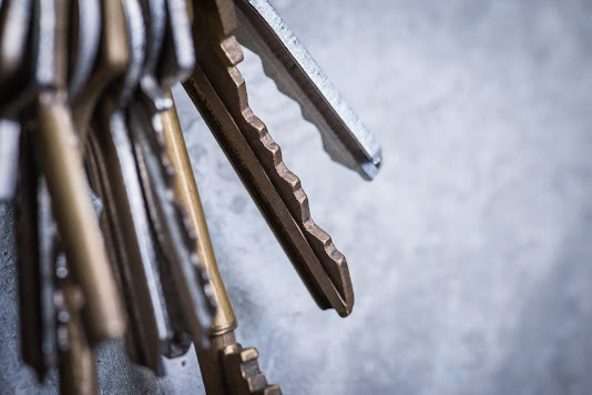 a bunch of old worn keys hanging on the screw on the grey concrete wall